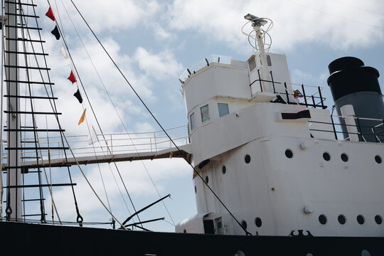 A ship's mast with signal flags at the top and rope lines