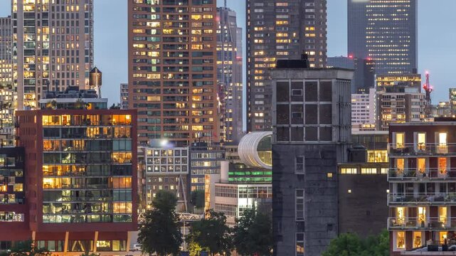 Aerial day to night transition timelapse of Katendrecht peninsula and Maashaven harbour in Rotterdam, The Netherlands. City skyline modern skyscrapers with glowing and blinking windows after sunset