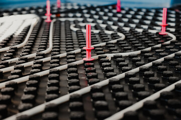 Installing underfloor heating system with white pipes and pink holders