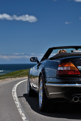 Fototapeta premium Luxury Convertible Car Driving Winding Coastal Highway Summer Road Trip Vacation Freedom Travel