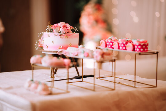 strawberry themed cake and deserts arranged on a party table