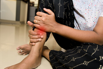Kneeling woman experiencing ankle pain indoors