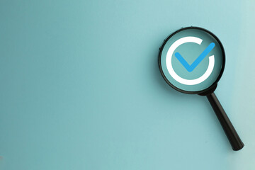 Magnifying glass with checkmark icon on pastel blue background. Concept of quality assurance,...
