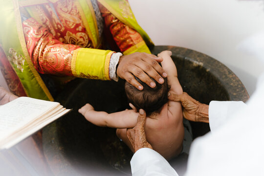 priest blessing baby during baptism