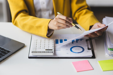 Serious female accountant working with financial documents in office and auditing accounts. Auditor checking financial report documents on desk.