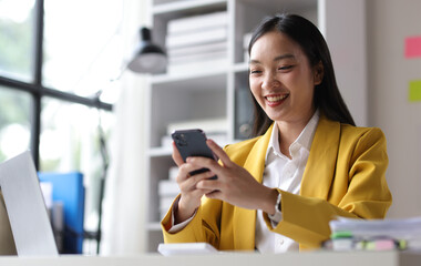 Happy businesswoman using mobile phone and sending messages online on smartphone.