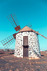 View of the old, typical windmills of Villaverde, Fuerteventura, Canary Islands, with their wooden blades. almost sunset, oblique light, golden hour. Past, vintage feeling.