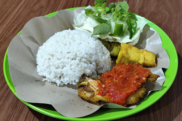 Fried Chicken Lalapan, a traditional Indonesian meal that includes rice with fresh vegetables, and mashed chili sauce.