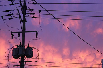 Electric Utility Pole and Power Lines Against Dramatic Sunset Sky