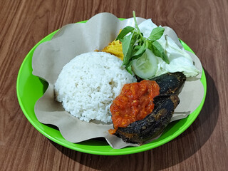 Lalapan lele, traditional Indonesian food with fresh vegetables and mashed chili sauce.