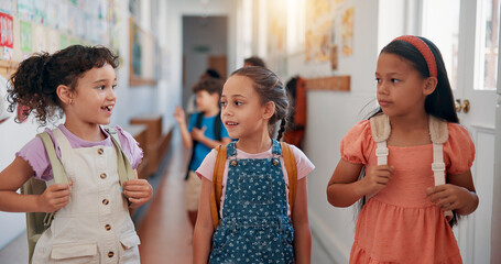 Children, friends and talking in corridor at school for education, learning or recess. Happy girls, classmates and students walk to class together for development, knowledge or growth in elementary