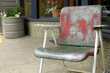 The red colored chair is just outside of the store.