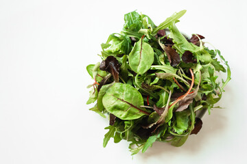 Mix of fresh green salad with arugula, beetroot leaves, basil on a white background. Detox,...