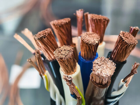 Various types of electrical wires showing copper strands and insulation in a workshop setting