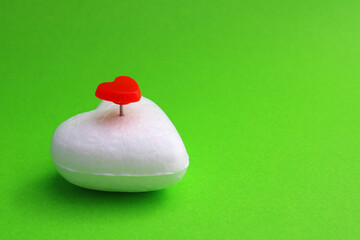 Red heart-shaped pushpin on another white foam heart