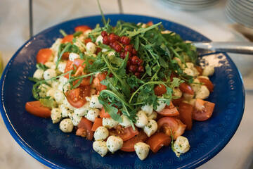 salad with tomatoes, mozzarella and arugula on a blue plate