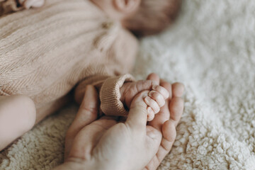 Happy Mothers day! Happy Fathers day! Parents holding newborn baby hand close up. Love and family concept. Dad and mom bonding with sweet little infant. Adoption and care