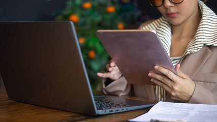 Businesswoman working diligently with technology devices in the office with tablet and laptop on the desk.