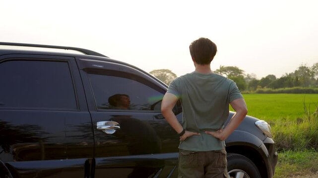 Man driver is stretching after a long dirve. He exercises his body to relieve his body pain at natural sunset view.  Flare light.