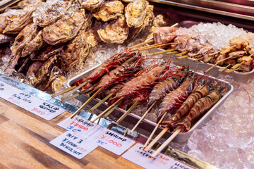 Selection of fresh seafood including skewered tiger prawns squid and scallops is arranged on...