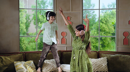 Indian Asian happy cute child kid boy with young adult gen z teen age girl wear headphone on cozy...