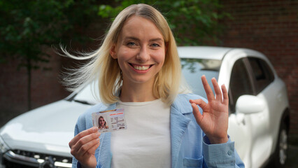 Satisfied Caucasian businesswoman owner female girl looking at camera showing license driver school...