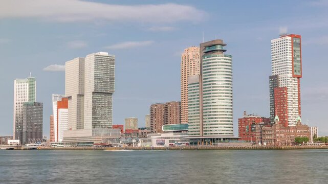 Rotterdam skyline timelapse from Nieuwe Maas River bank to Wilhelminapier and Kop van Zuid. Modern skyscrapers, ship terminal and waterfront in this redeveloped former harbor area with boats passing