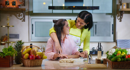 Indian happy woman lady with cute teen age cute girl rolling raw flour dough learn cooking food indoor home smiling young mom teach to kid child baking cookies enjoy day indoor modern home kitchen