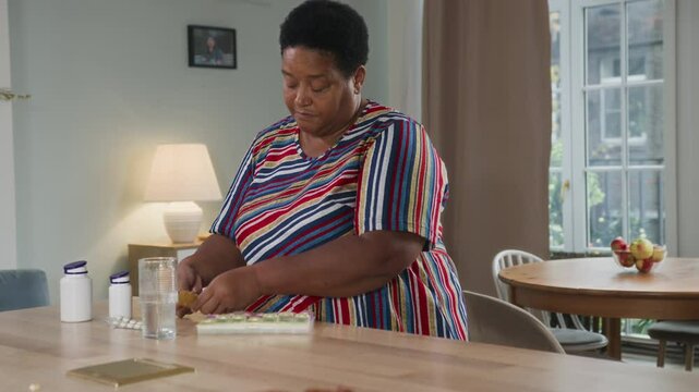 Senior afro woman sorting pillbox at table. Aged woman putting vitamins in pills organizer. Older organized woman doing health care and therapy. Female elegant retired using medicine container