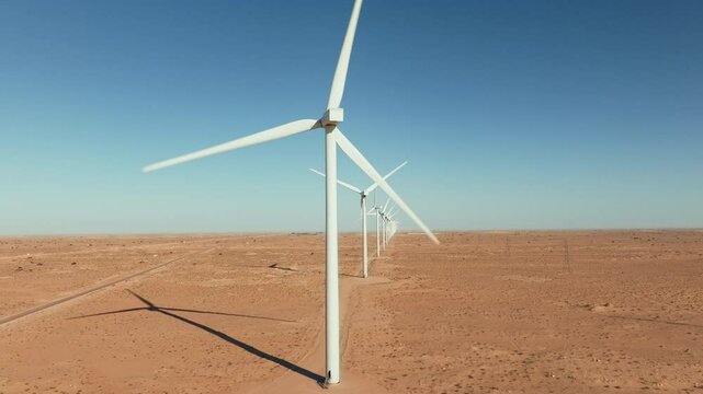 Drone view of spinning wind turbines in the desert