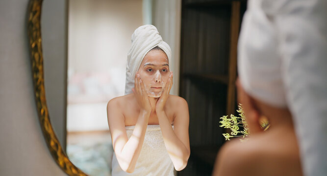 Indian young adult gen z woman lady teen girl female wrapped towel on head and body look mirror use fresh foam soap apply wet dry cheek take sink water hand splash on face do self skin care day home	