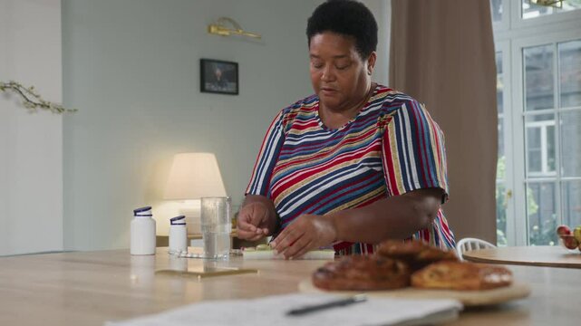 Senior afro woman sorting pillbox at table. Aged woman putting vitamins in pills organizer. Older organized woman doing health care and therapy. Female elegant retired using medicine container