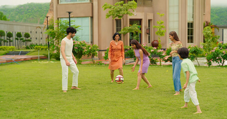 Indian happy family young man woman group play ball game throwing in air have fun joy enjoy outdoor...