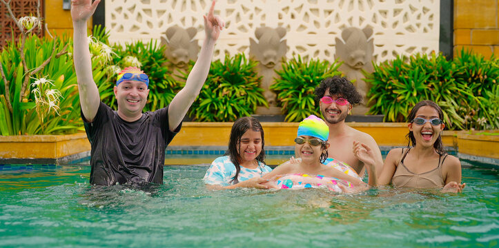 Indian happy family group with teen child look cam do funny pose enjoy outdoor resort pool trip Asian dad man male young adult girl boy female have fun joy spend day time at outside water park villa