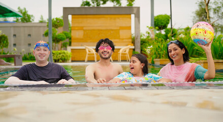 Indian happy family group with teen child dancing look cam enjoy outdoor resort pool edge trip mom dad young adult girl boy make female do pose have fun joy spend day time at outside water park