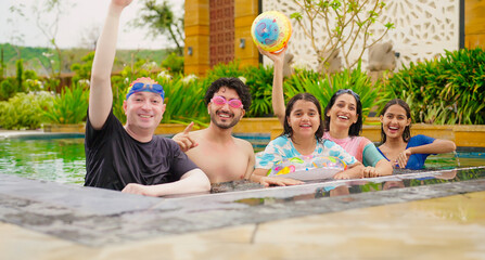 Indian happy family group with teen child dancing look cam enjoy outdoor resort pool edge trip mom dad young adult girl boy make female do pose have fun joy spend day time at outside water park