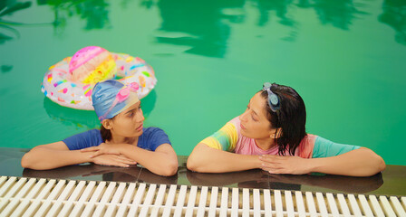 Indian relax wet adult mom woman with cute teen girl standing take rest on pool edge feel tired....