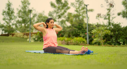 Indian mature adult older gen x woman lady sitting on yoga mat do stretch warm up asana in fresh...