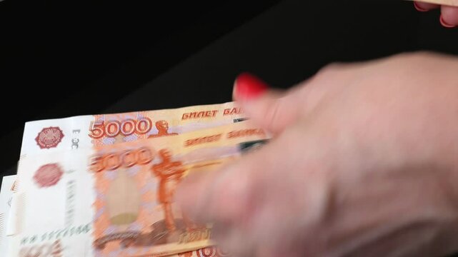 Fingers count a lot of five thousand Russian ruble banknotes. A close-up of Bank of Russia banknotes with a face value of five thousand rubles, a woman's hand counting out Russian money.