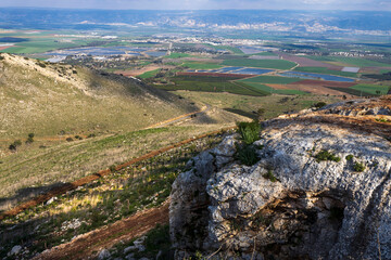 Fototapeta premium A panorama from Mount Gilboa Israel featuring pines, flora, the valley, and the Jordanian mountains, with clouds overhead and farmland stretching below.