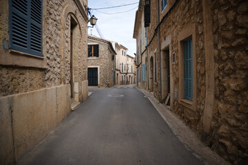 A narrow street with a stone wall on the side in alaro mallorca
