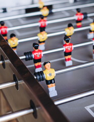 Group of friends playing kicker in a sports bar room, colleagues teammates play table football,...