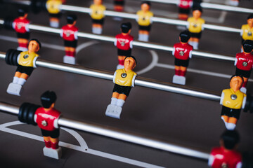 Group of friends playing kicker in a sports bar room, colleagues teammates play table football,...