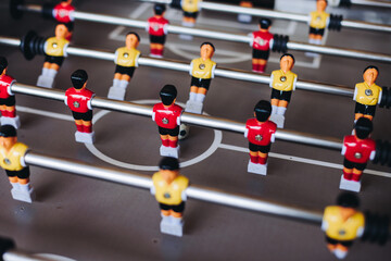 Group of friends playing kicker in a sports bar room, colleagues teammates play table football,...