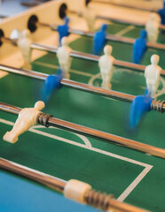 Group of friends playing kicker in a sports bar room, colleagues teammates play table football, table soccer game in the office, having fun, tabletop football match competition at work, backyard games