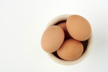 Fresh Brown Eggs Arranged in a Small Bowl on a White Background