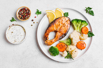 Grilled salmon fish steak with steamed vegetables and tzatziki sauce