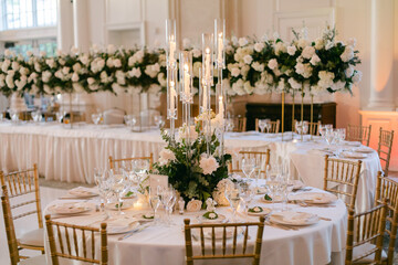 Elegant wedding reception setup with floral arrangements and candlelight in a bright venue