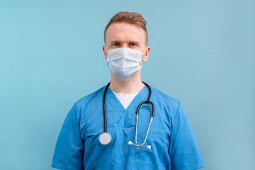 Portrait of a young Caucasian male doctor in a blue uniform on an isolated background. Male...