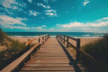 Naklejka premium Sunny boardwalk leading to a serene beach with calm waves under a bright blue sky